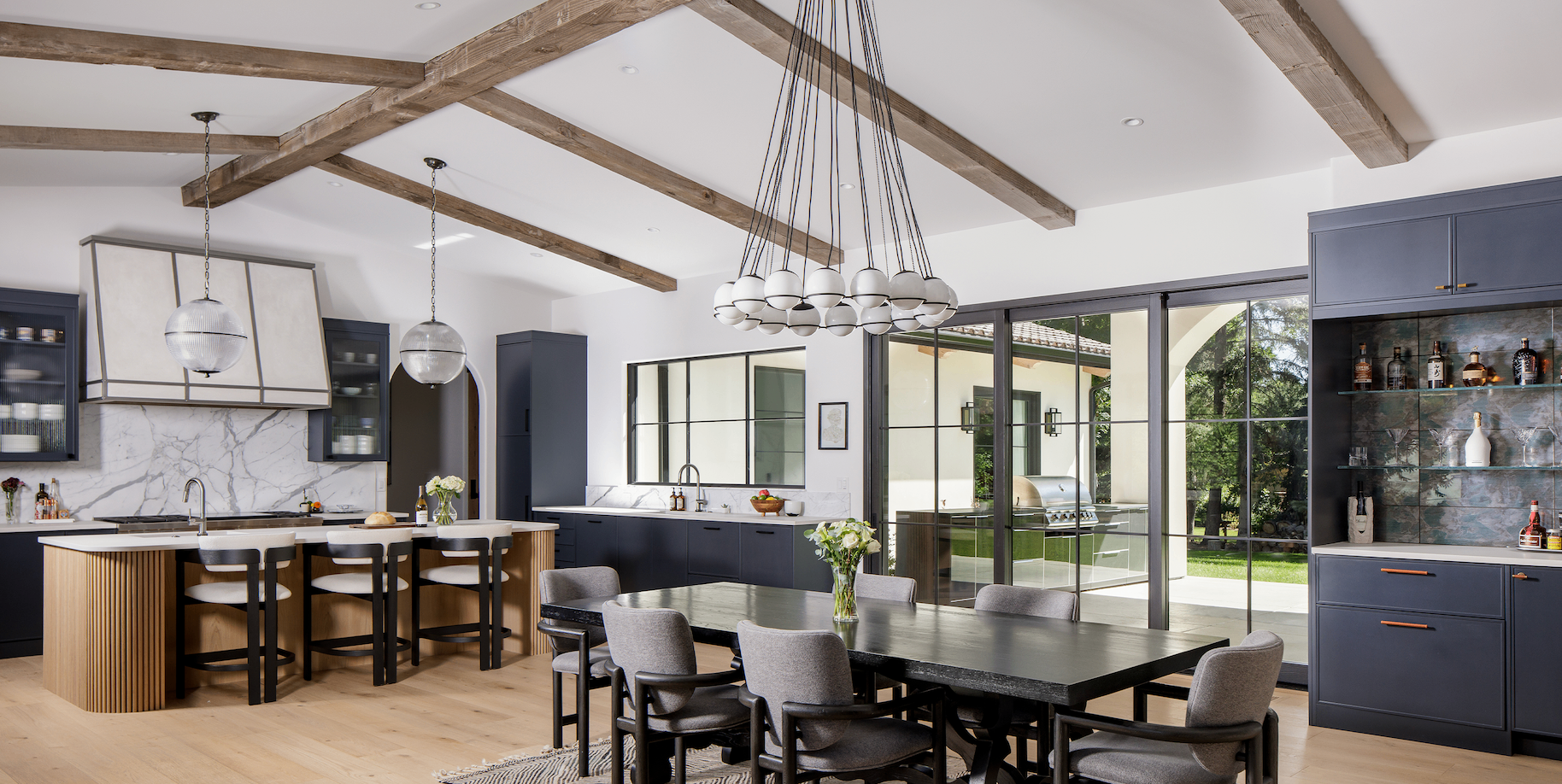 Open kitchen and dining room with exposed timber beams and steel doors