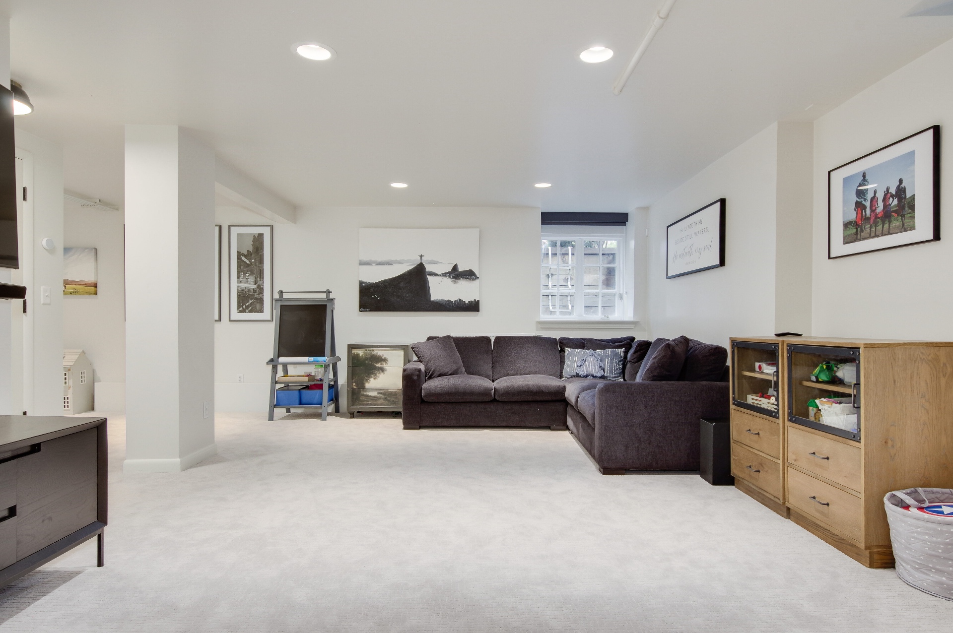 Lower-level entertainment room with a sectional and gallery wall