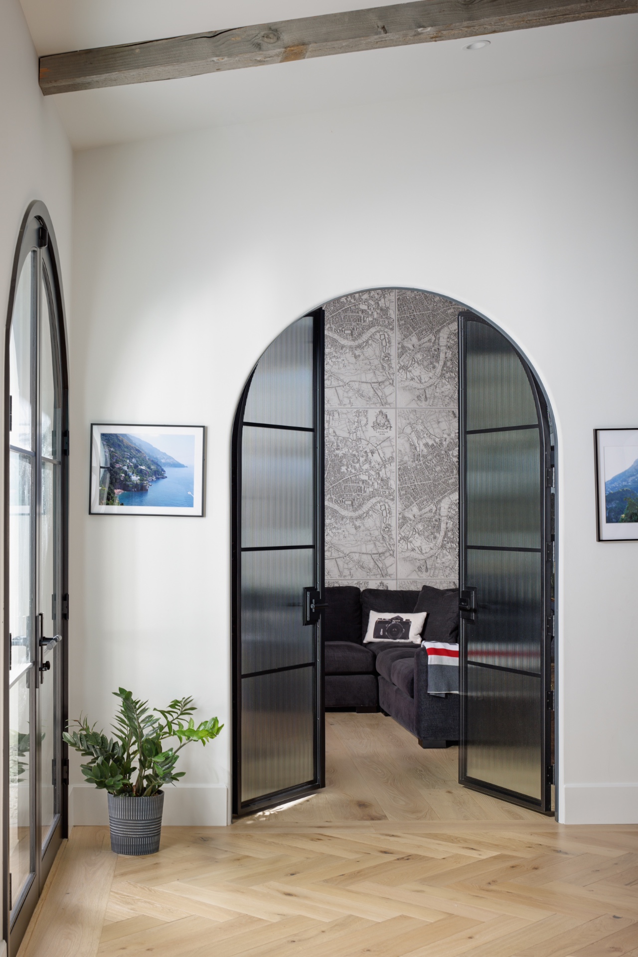 Arched steel-and-reeded-glass doors opening to a media room