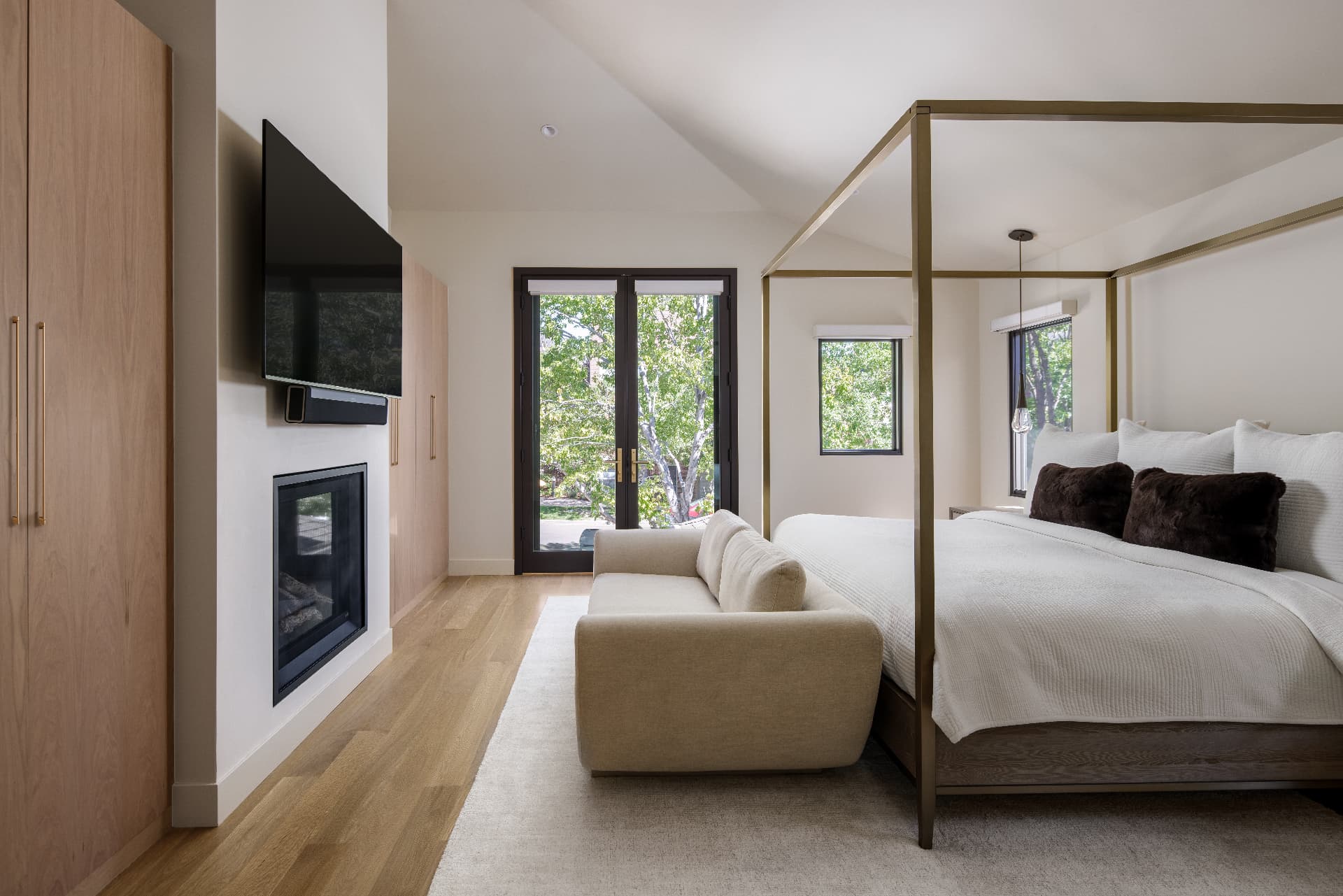 Cherry Creek primary bedroom with brass canopy bed, fireplace, and garden doors