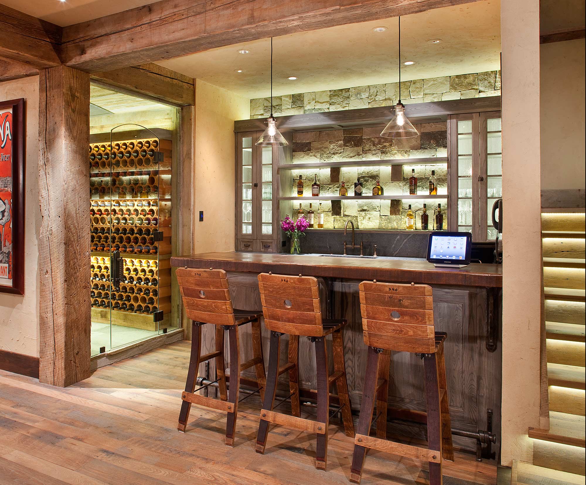 Lower-level bar with a glass wine room and stone backsplash