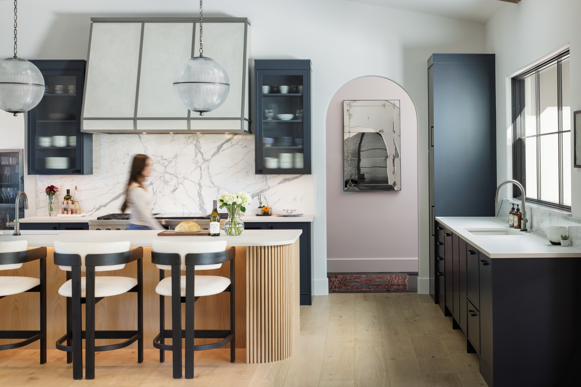 Custom kitchen with marble backsplash, fluted island, and globe pendants