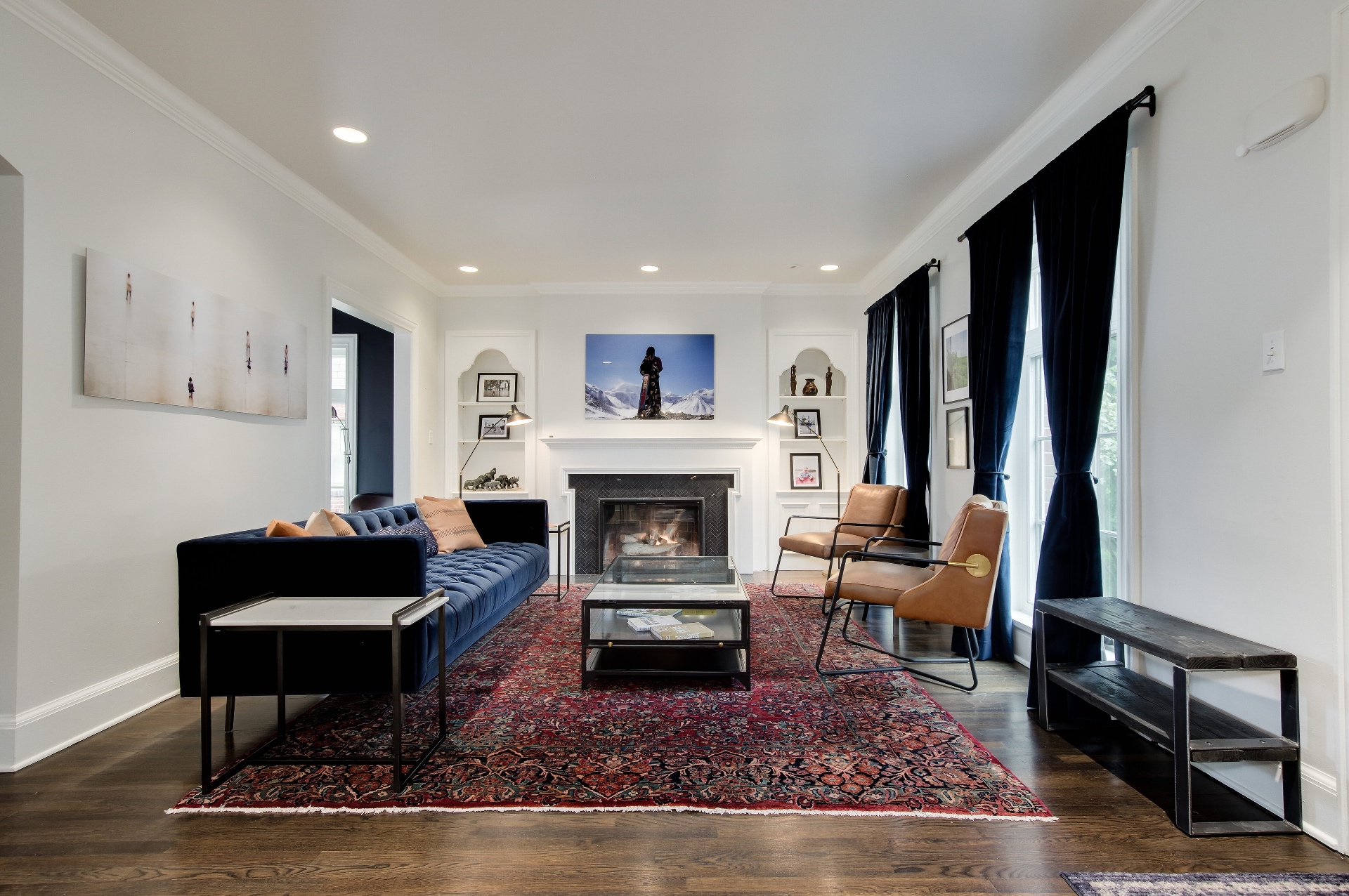 Living room with a velvet sofa, herringbone-tiled fireplace, and arched built-ins