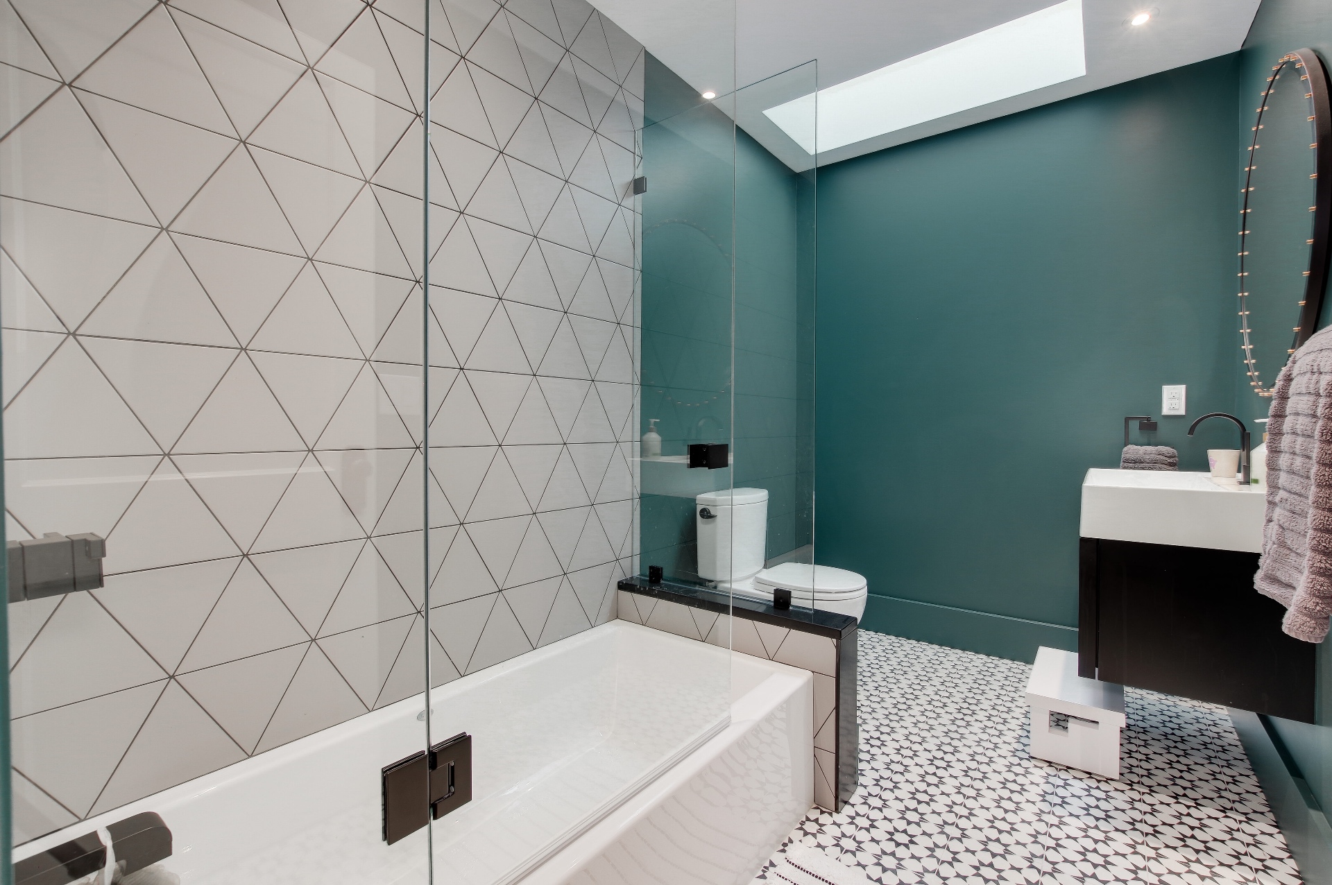 Guest bath with geometric tile, a skylight, and deep teal walls