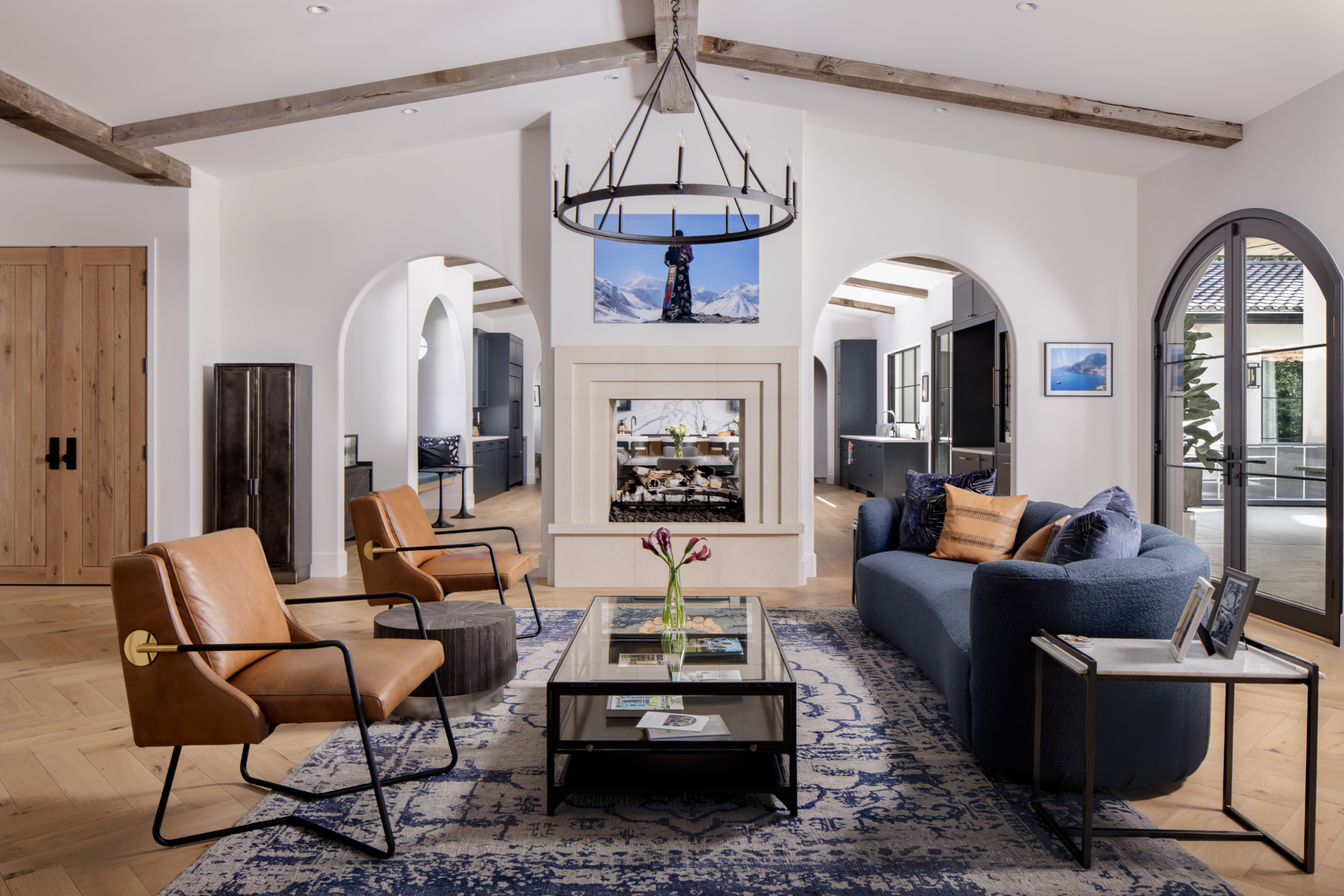 Living room with vaulted timber beams, limestone fireplace, and leather chairs