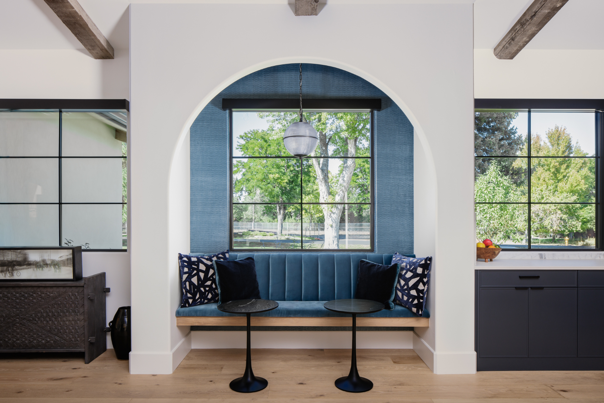 Arched breakfast nook with a blue velvet banquette and globe pendant
