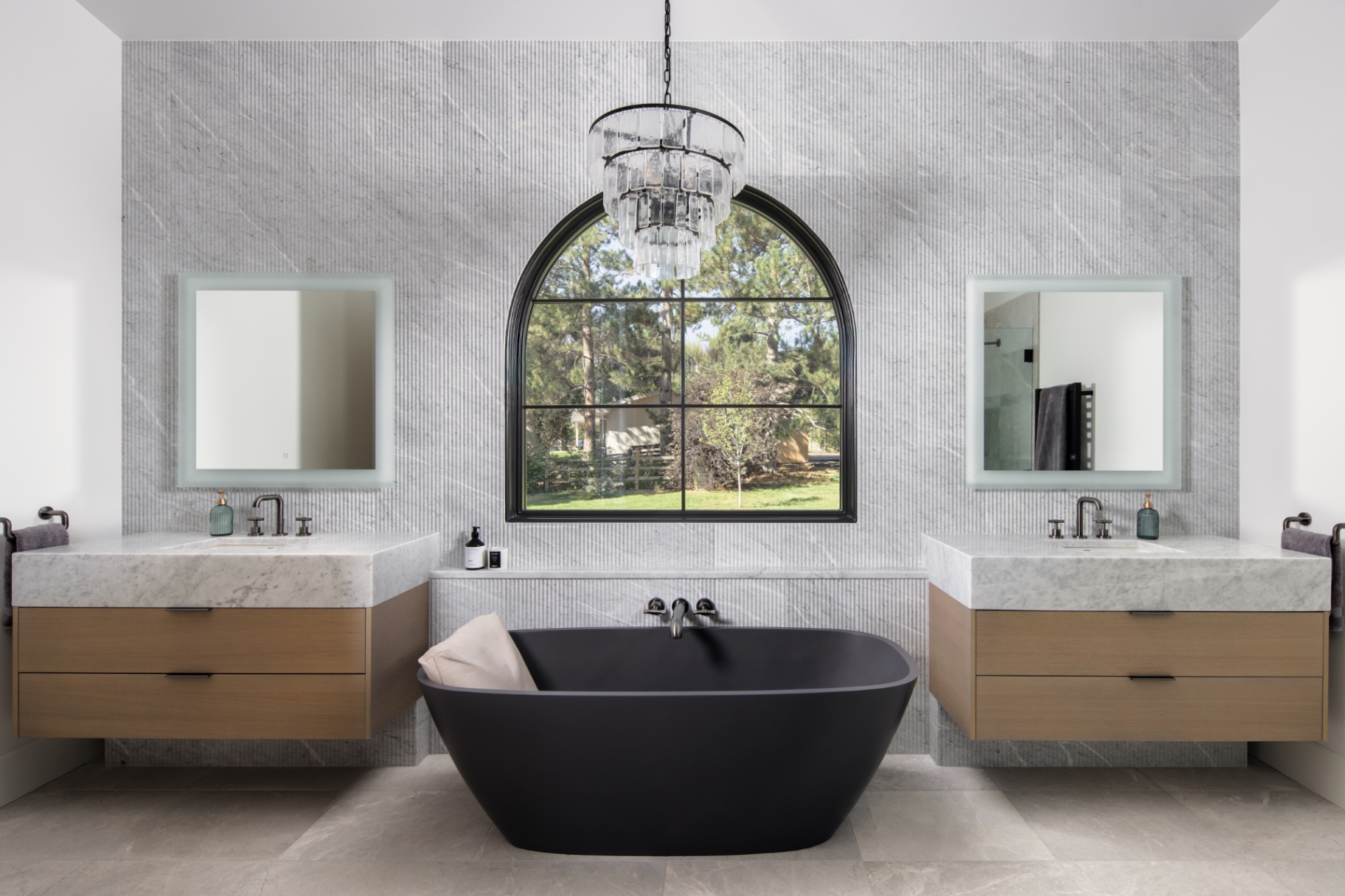 Primary bath with a black soaking tub beneath an arched window