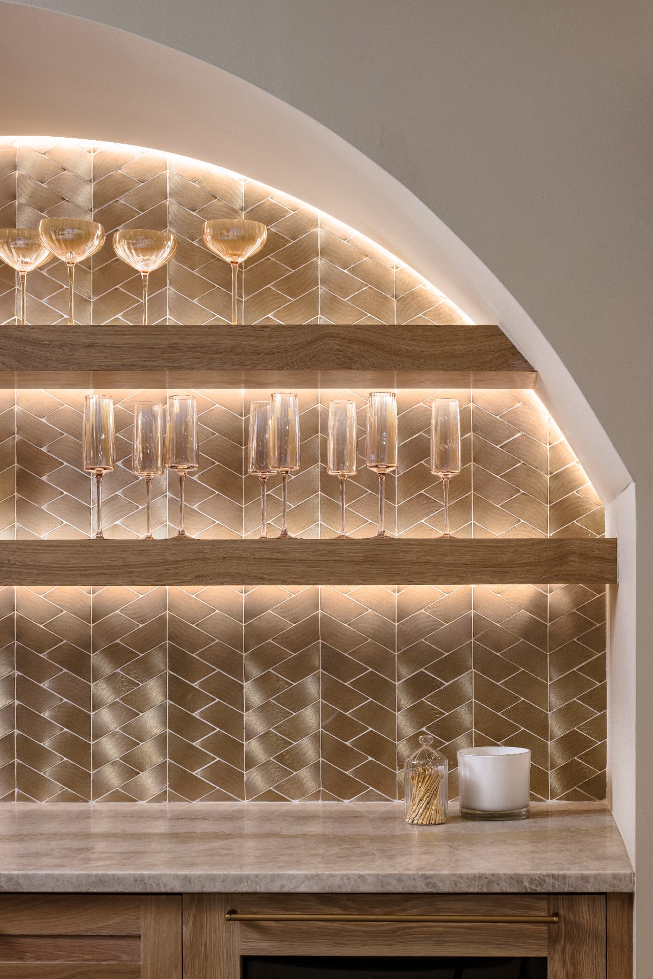 Cherry Creek bar detail with herringbone tile, lit shelves, and glassware