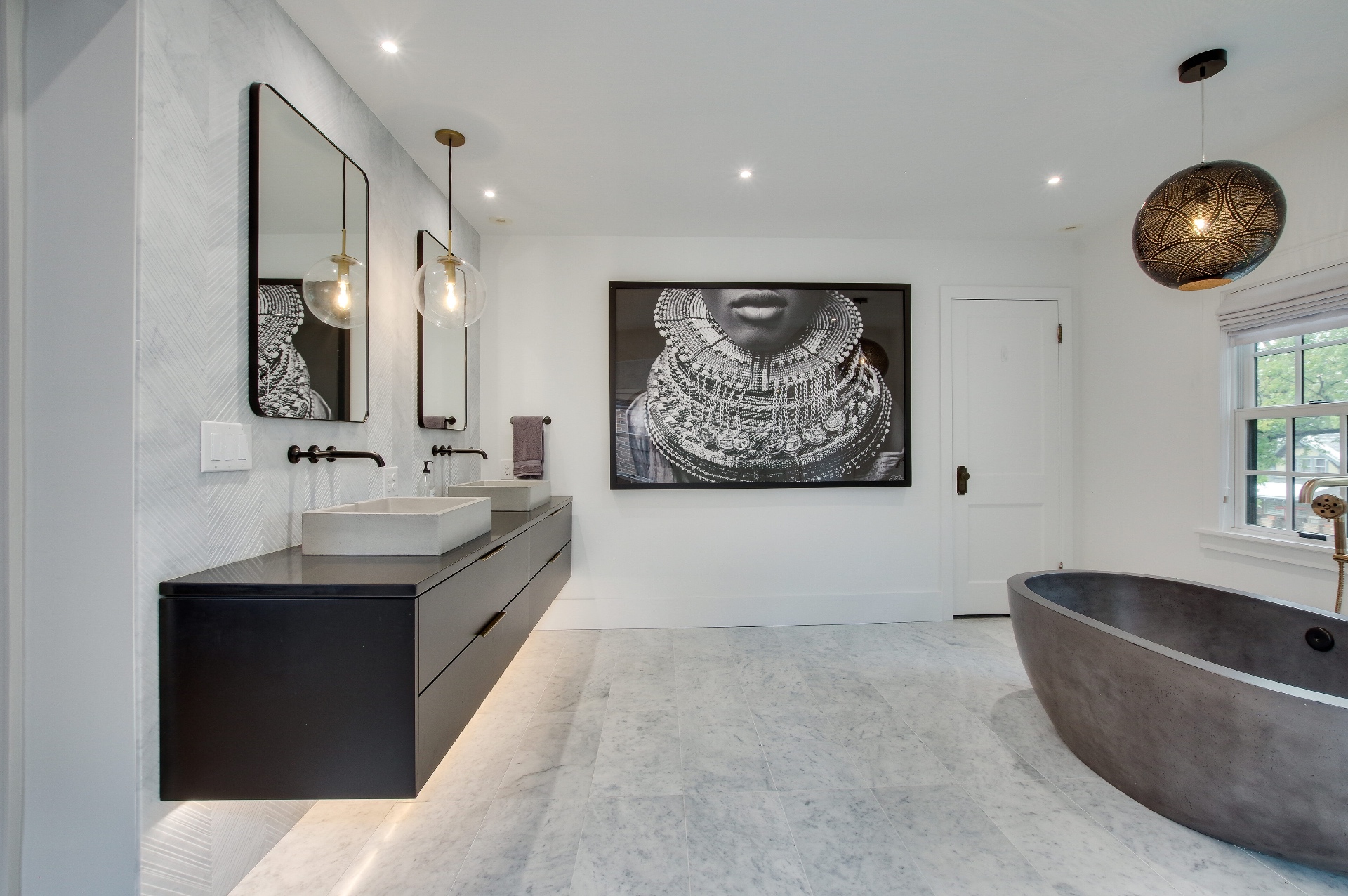 Primary bath with a floating vanity, marble floors, and a stone soaking tub