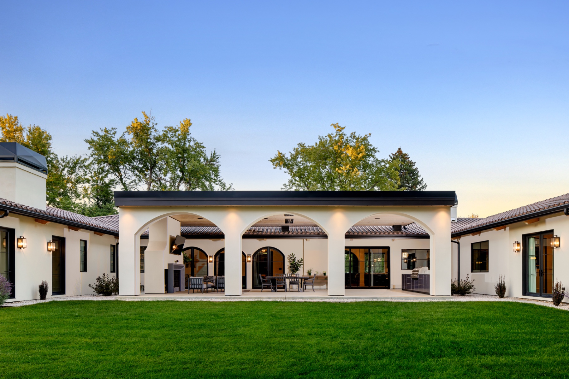 Rear arched loggia and courtyard lawn at dusk