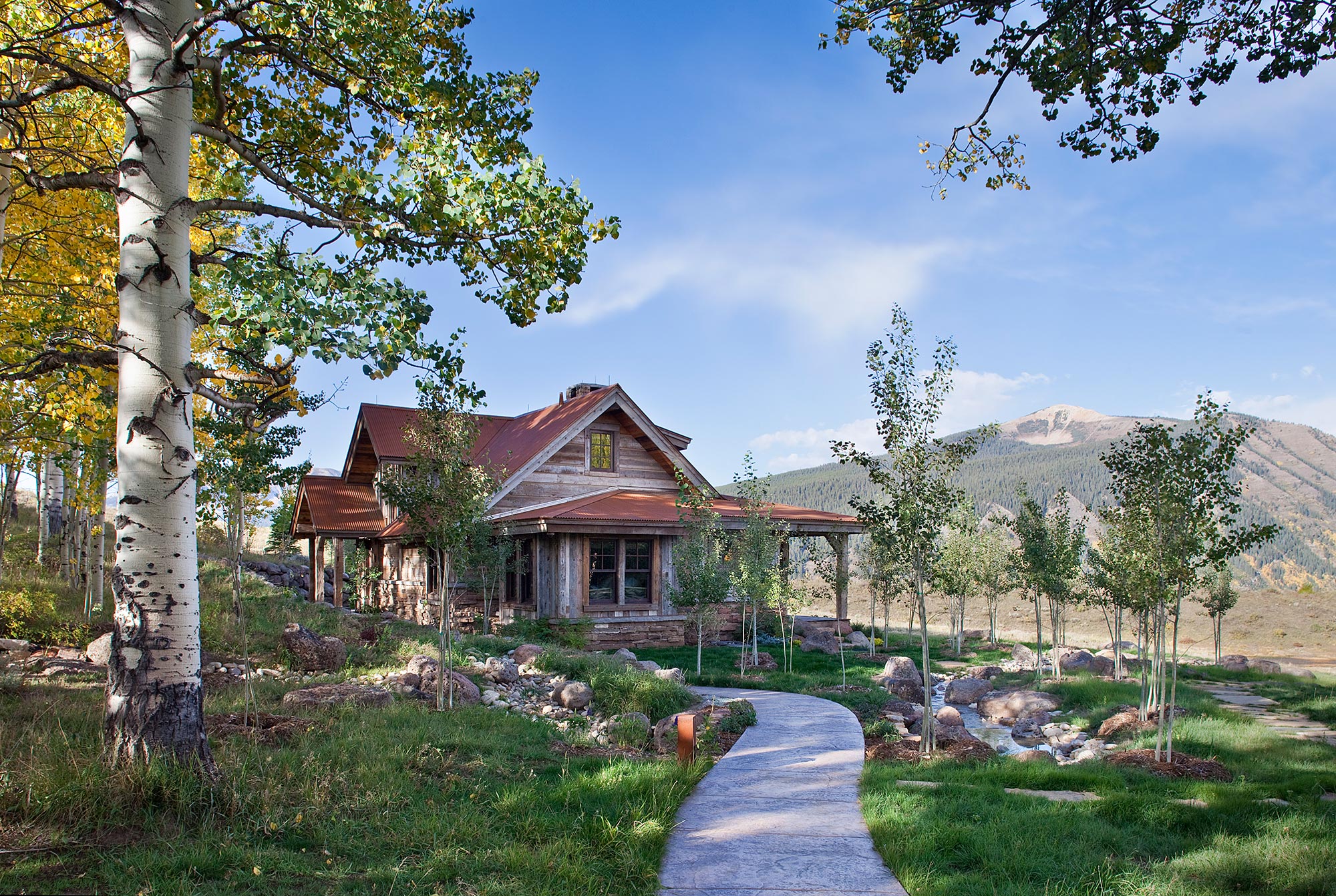Timber residence framed by golden aspens with the mountain beyond