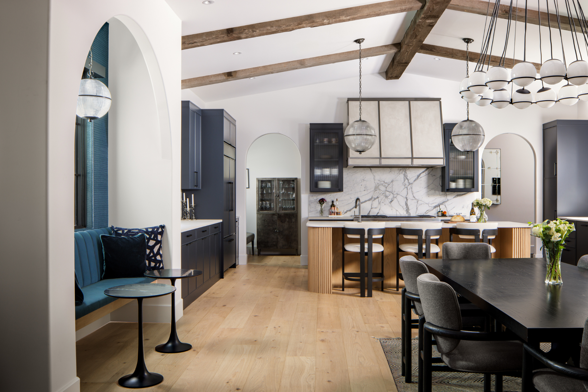 Kitchen with marble backsplash, fluted island, and globe pendants