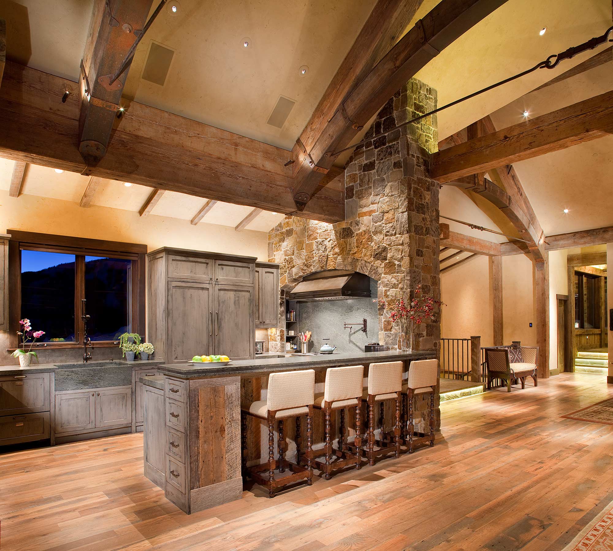 Open kitchen with a stone hearth chimney and concrete counters