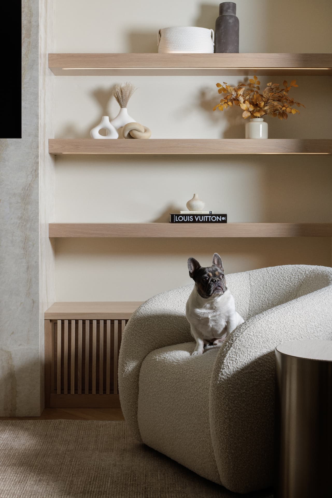 Cherry Creek living room shelving wall with backlit oak shelves and bouclé chair