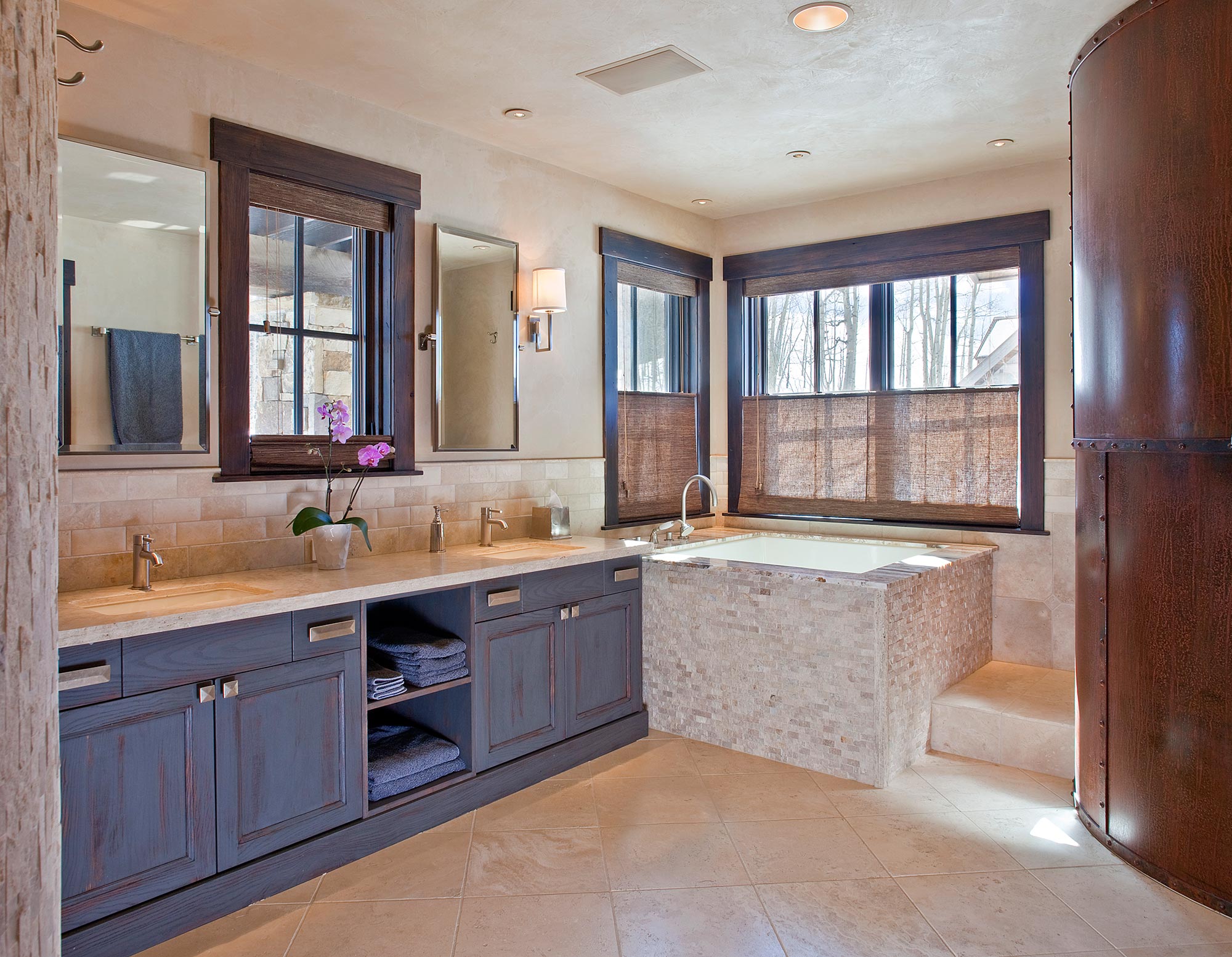 Primary bath with a stone-tiled soaking tub and travertine floors
