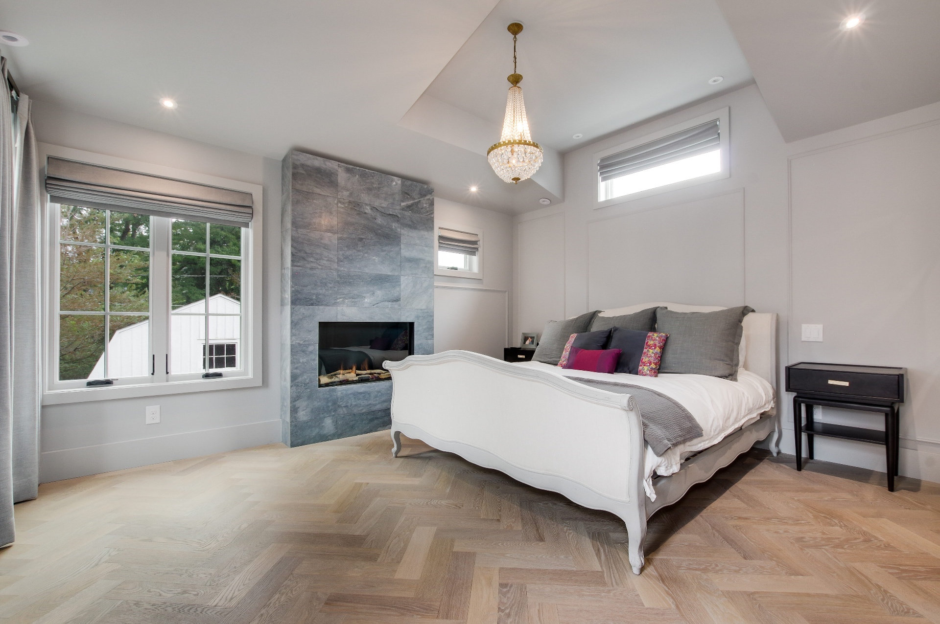 Primary bedroom with a stone fireplace and herringbone oak floors